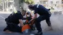Polisi menggunakan gergaji beton untuk memotong bagian aspal di dekat tangan seorang aktivis iklim yang menempelkan tangannya untuk menarik perhatian pada aksi keadaan darurat iklim, pada tanggal 18 September 2023 di Berlin. (Odd ANDERSEN/AFP)