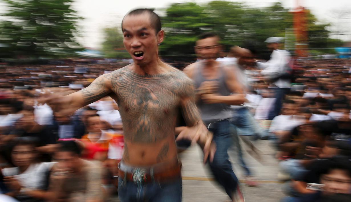 Pria bertato berlari saat kesurupan selama Festival Tato Suci di kuil Wat Bang Phra, Nakhon Pathom, Thailand (16/3). Mereka percaya tato memiliki kekuatan mistis, menangkal nasib buruk dan melindungi mereka dari bahaya. (Reuters/Athit Perawongmetha)