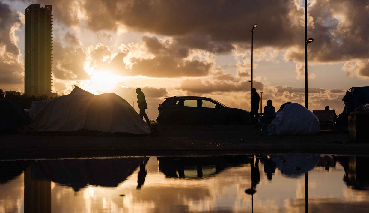 Di sisi lain, Kementerian Kesehatan Lebanon, pada Jumat 27 Maret 2026, melaporkan jumlah korban tewas akibat serangan Israel sejak 2 Maret 2026 telah mencapai 1.142 jiwa. Tampak dalam foto, para pengungsi berdiri di samping tenda mereka di sepanjang kawasan tepi laut Beirut, Lebanon, pada Senin 30 Maret 2026. (Dimitar DILKOFF/AFP)