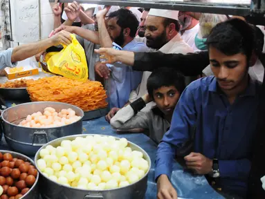 Orang-orang membeli penganan manis tradisional di hari raya Idul Fitri di Peshawar, Pakistan barat laut, pada 25 Mei 2020. Warga Pakistan memiliki tradisi memakan penganan manis saat merayakan Idul Fitri, yang menandai akhir bulan puasa Ramadan. (Xinhua/Saeed Ahmad)