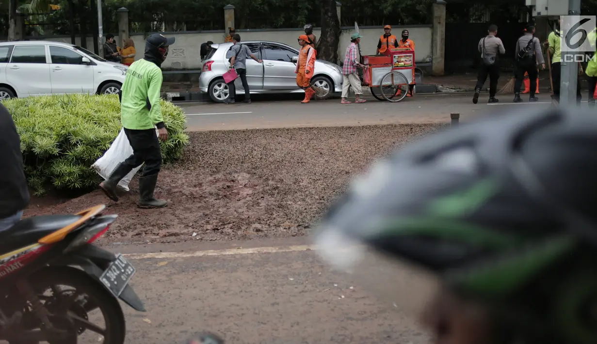 Kondisi lalu lintas saat petugas pertamanan membersihkan tanaman dan rumput yang rusak terinjak-injak usai unjuk rasa massa Partai Hanura di depan Gedung KPU, Jakarta, Senin (21/1). (Liputan6.com/Faizal Fanani)