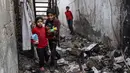 Anak-anak membawa barang-barang makanan yang diselamatkan dari rumah mereka yang rusak saat mereka menemukan jalan melalui gang yang tertutup puing-puing, setelah pengeboman Israel di Rafah, Jalur Gaza selatan pada 25 Februari 2024. (SAID KHATIB/AFP)