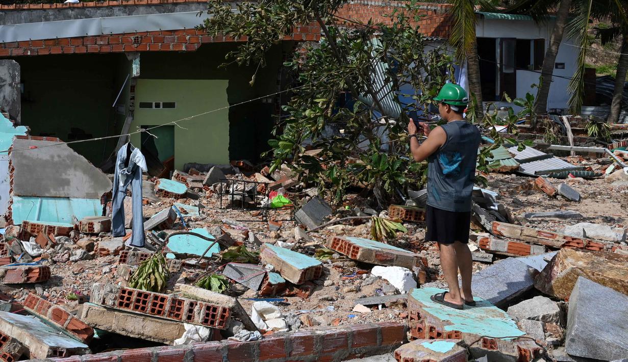Sedikitnya lima orang dikabarkan tewas, sementara tujuh lainnya terluka. Tampak dalam foto, seorang warga merekam puing-puing bangunan yang hancur akibat angin kencang di ponselnya di desa nelayan Nhon Hai dekat Quy Nhon, Provinsi Gia Lai, Vietnam Tengah, pada Jumat 7 November 2025. (NHAC NGUYEN/AFP)