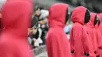 Orang-orang berpakaian seperti penjaga Squid Games dengan berdiri di area penonton selama pertandingan lanjutan Liga Inggris 2024/2025 antara Tottenham Hotspur melawan Liverpool di Stadion Tottenham Hotspur, London, Inggris Minggu (22/12/2024). Seperti diketahui, aksi tersebut ternyata merupakan promo musim kedua serial Korea Selatan tersebut. (AFP/Glyn Kirk)