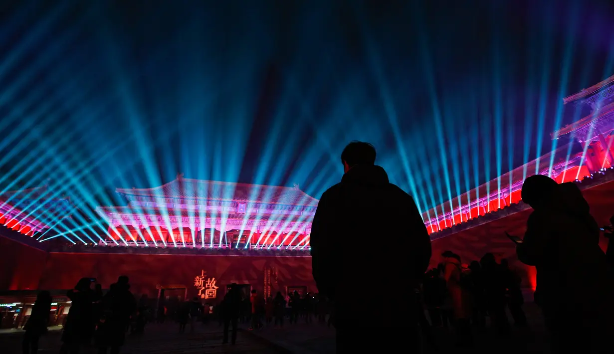 Pengunjung menyaksikan dinding gerbang utama Wu Men Kota Terlarang atau Forbidden City  yang diterangi pertunjukan cahaya selama perayaan Festival Lentera di Beijing, Selasa (19/2). Festival itu menandai berakhirnya liburan Tahun Baru Imlek (AP/Andy Wong)