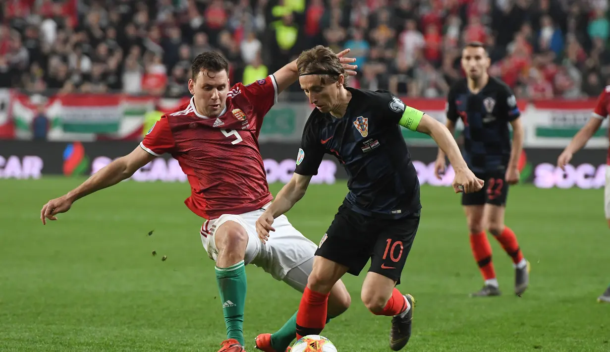 Aksi Luka Modrid melewati pemain Hungaria, Adam Szalai pada laga kedua babak kualifikasi Piala Eropa 2020 Grup E yang berlangsung di Stadion Groupama Arena, Budapest, Senin (25/3). Kroasia kalah 1-2 kontra Hungaria. (AFP/Attila Kisbenedek)