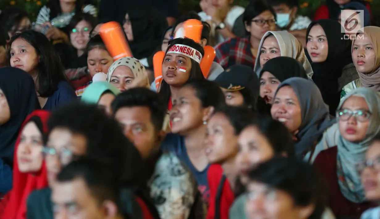 Suporter tim bulutangkis Indonesia terlihat tegang saat menyaksikan siaran langsung laga perempat final dan 16 besar bulutangkis Asian Games 2018 melalui layar lebar di kawasan kompleks GBK, Jakarta, Sabtu (25/8). (Liputan6.com/Helmi Fithriansyah)