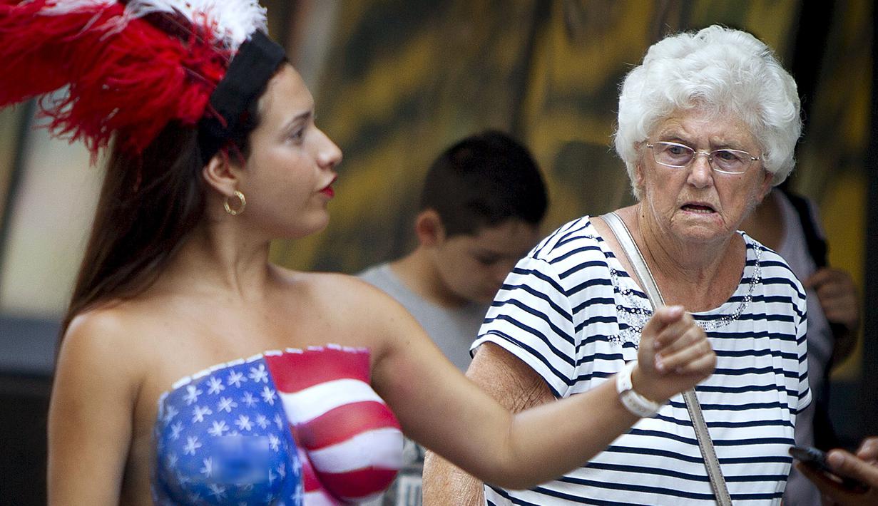 Seorang wanita dengan bertelanjang dada dipinggiran ruas jalan Times Square, New York,AS,  Selasa (18/8/2015). Mereka meminta uang kepada para wisatawan yang ingin mengajak foto bersama dengan tanpa memakai busana. (REUTERS/Carlo Allegri)