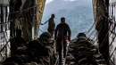Pesawat-pesawat ini memiliki peran vital dalam menjangkau area terpencil dan membawa bantuan dalam jumlah besar. Tampak dalam foto, personel Tentara Nasional Indonesia (TNI) Angkatan Udara (AU) bersiap untuk menurunkan bantuan dari pesawat angkut militer di wilayah Gayo Lues, Aceh, yang terdampak banjir dan terisolasi pada Minggu 7 Desember 2025. (HENDRA SYAMHARI/AFP)