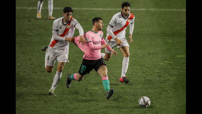 Pemain Rayo Vallecano, Santiago Comensano menarik baju pemain Barcelona, Lionel Messi pada laga babak 16 Besar Copa del Rey di Vallecas stadium, Madrid, Kamis (28/1/2021). (Foto: AP/Manu Fernandez)
