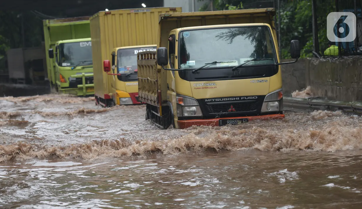 Sejumlah truk melewati banjir yang merendam terowongan di Cawang, Jakarta, Jumat (19/2/2021). Hujan yang turun sejak semalam membuat sejumlah jalanan di Ibu Kota tergenang banjir dengan ketinggian sekitar 30-50 cm. (merdeka.com/Imam Buhori)