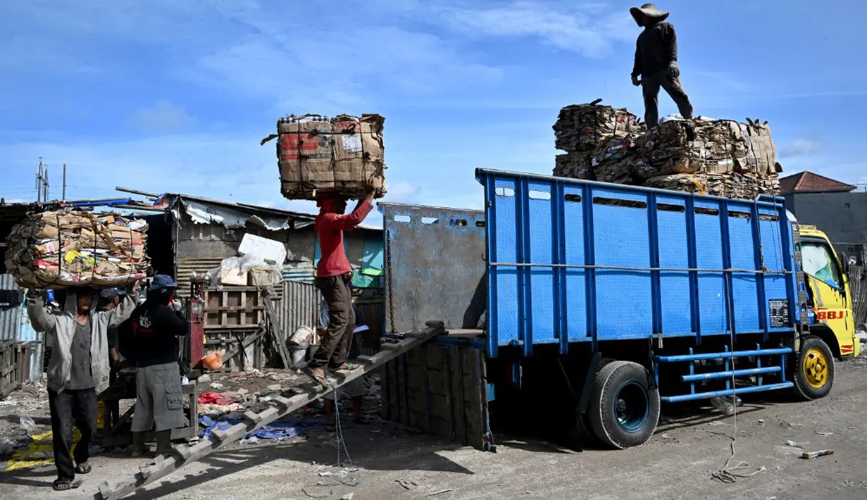Orang-orang memuat kertas bekas ke truk setelah ditimbang sebelum dijual ke pemulung di Denpasar, Bali, Sabtu (20/1/2024). Pemerintah Kota Denpasar membangun sinergi dengan para pemangku kepentingan terkait untuk mengoptimalkan upaya penanganan sampah di wilayahnya. (SONNY TUMBELAKA/AFP)