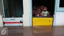 Seorang anak di dalam rumah memperhatikan banjir di kawasan Jatayu, Jakarta, Senin (21/11). Karena tingginya curah hujan serta buruknya drainase air menyebabkan meluapnya Kali Pesanggrahan yang mengakibatkan banjir. (Liputan6.com/Gempur M. Surya)