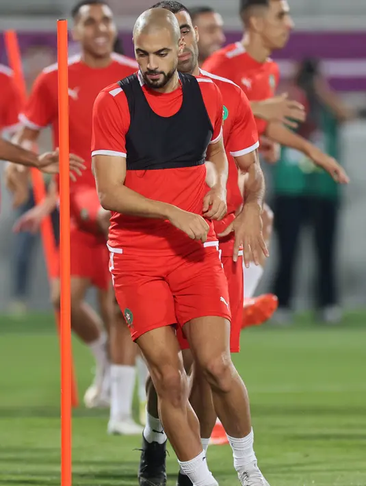 elandang Maroko,  Sofyan Amrabat melakukan pemanasan selama mengikuti sesi latihan tim di Stadion Al Duhail SC di Doha (16/12/2022). Maroko akan bertanding melawan Kroasia untuk memperebutkan juara 3 Piala Dunia 2022. Keduanya dipertemukan kembali setelah pernah bertanding pada babak penyisihan grup F lalu. (AFP/Karim Jafaar)
