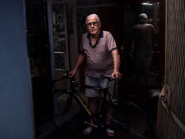 Raffaello Bianco, mekanik dan pecinta sepeda berpose di pintu masuk bengkel mekaniknya di ruang bawah tanah apartemennya di Turin, Italia, 7 Juli 2020. Raffaello Bianco adalah montir sepeda amatir yang sedang memperbaiki sepeda di garasi kecil dekat rumahnya. (MARCO BERTORELLO/AFP)