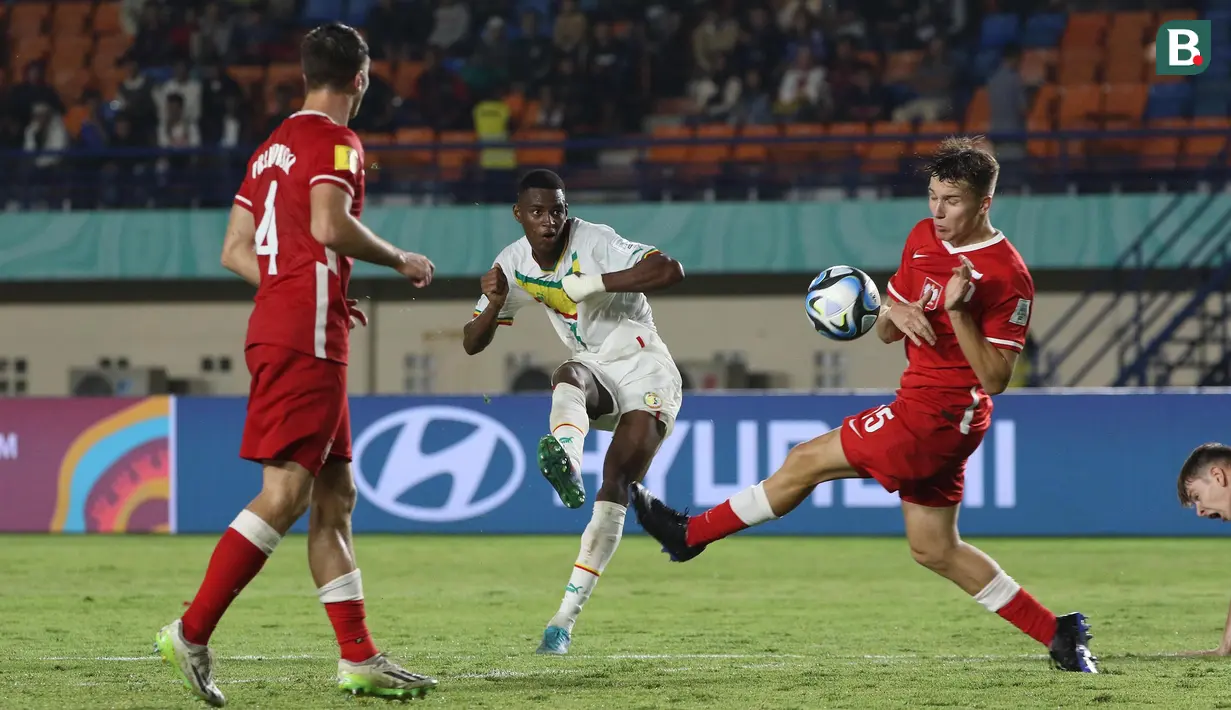 <p>Pemain Timnas Senegal U-17, Idrissa Gueye (tengah) melepaskan tendangan di antara dua pemian Timnas Polandia U-17, Igor Orlikowski (kiri) dan Piotr Kowalik pada laga kedua Grup D Piala Dunia U-17 2023 di Stadion Si Jalak Harupat, Kabupaten Bandung, Selasa (14/11/2023). (Bola.com/Ikhwan Yanuar)</p>