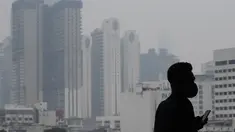 Seorang pria mengenakan masker saat kabut menyelimuti gedung-gedung di Kuala Lumpur (10/9/2019). Malaysia tengah mempersiapkan membuat hujan buatan setelah kualitas udara di sejumlah negara bagian mencapai level yang tidak sehat. (AFP Photo/Mohd Rasfan)