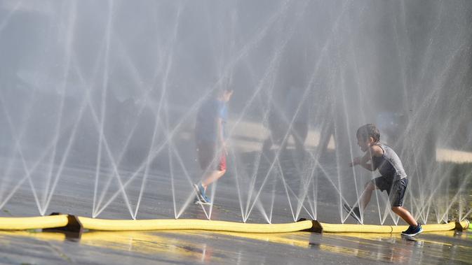 Anak-anak menyejukkan diri di dekat semprotan air di Schwarzenbergplatz di Wina, Austria (28/7/2020). Suhu tertinggi di Wina mencapai angka 37,2 derajat Celsius pada Selasa (28/7). (Xinhua/Guo Chen)