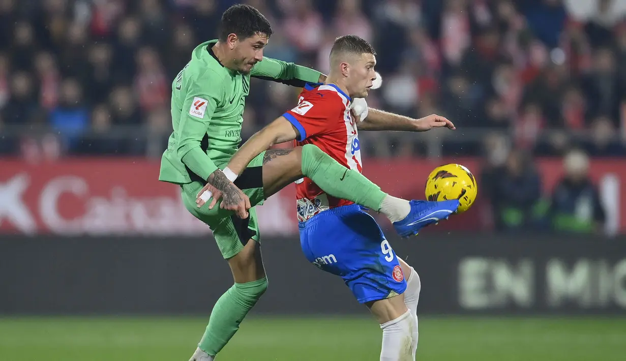 Bek Atletico Madrid, Jose Gimenez (kiri) berebut bola dengan striker Girona, rtem Dovbyk pada laga pekan ke-19 Liga Spanyol 2023/2024 di Montilivi Stadium, Girona, Kamis (4/1/2024) dini hari WIB. (AFP/Pau Barrena)