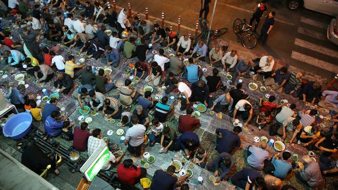 Warga muslim Iran menikmati menu makanan berbuka puasa di sebuah jalan di Teheran, 29 Mei 2018. Mereka yang sedang berpuasa dan berada jauh dari tempat tinggalnya mengikuti tradisi buka bersama di jalanan. (AP Photo/Vahid Salemi)