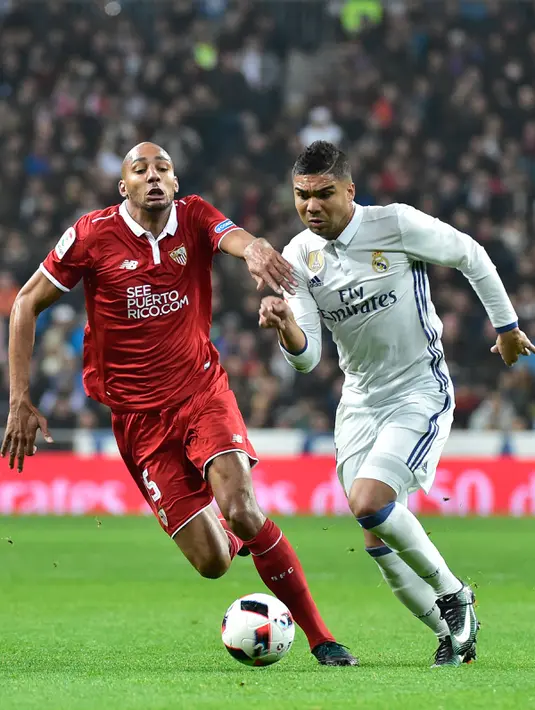 Gelandang Sevilla, Steven N'Zonzi (kiri) berebut bola dengan gelandang Real Madrid, Casemiro pada pertandingan pertama babak 16 besar Copa del Rey di Santiago Bernabeu, Spanyol (5/1). Madrid menang atas Sevilla 3-0. (AFP Photo/Gerard Julien)