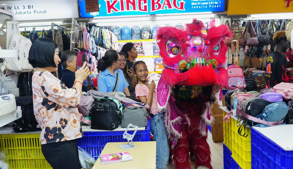 Tidak sedikit pengunjung yang berhenti sejenak untuk menyaksikan pertunjukan, bahkan mengabadikan momen tersebut melalui telepon genggam mereka. Tampak dalam foto, seorang penari barongsai tampil di Pusat Perbelanjaan Senen, Jakarta, Kamis 12 Februari 2026. (AP Photo/Tatan Syuflana)