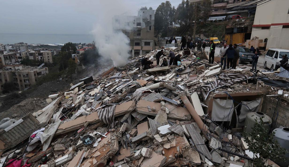 Beberapa laporan menunjukkan kerusakan signifikan pada bangunan pemukiman warga akibat bombardir tersebut. Tampak dalam foto, asap mengepul saat orang-orang memeriksa bangunan yang hancur akibat serangan Israel di desa Qennarit, Lebanon selatan, Kamis 22 Januari 2026. (AP Photo/Mohammed Zaatari)