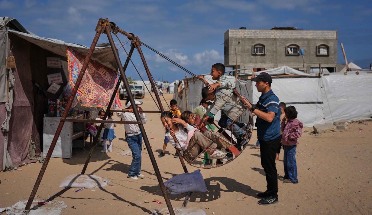 Anak-anak pengungsi Palestina bermain ayunan di sebuah kamp tenda selama Hari Raya Idul Adha di Khan Younis, Jalur Gaza Selatan, Rabu 27 Mei 2026. (AP Photo/Abdel Kareem Hana)