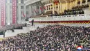 Orang-orang mengibarkan bendera nasional saat pemimpin Korea Utara Kim Jong-un (tengah atas) menghadiri parade militer menandai kongres partai yang berkuasa di Lapangan Kim Il-sung, Pyongyang, Korea Utara, Kamis (14/1/2021). (Korean Central News Agency/Korea News Service via AP)