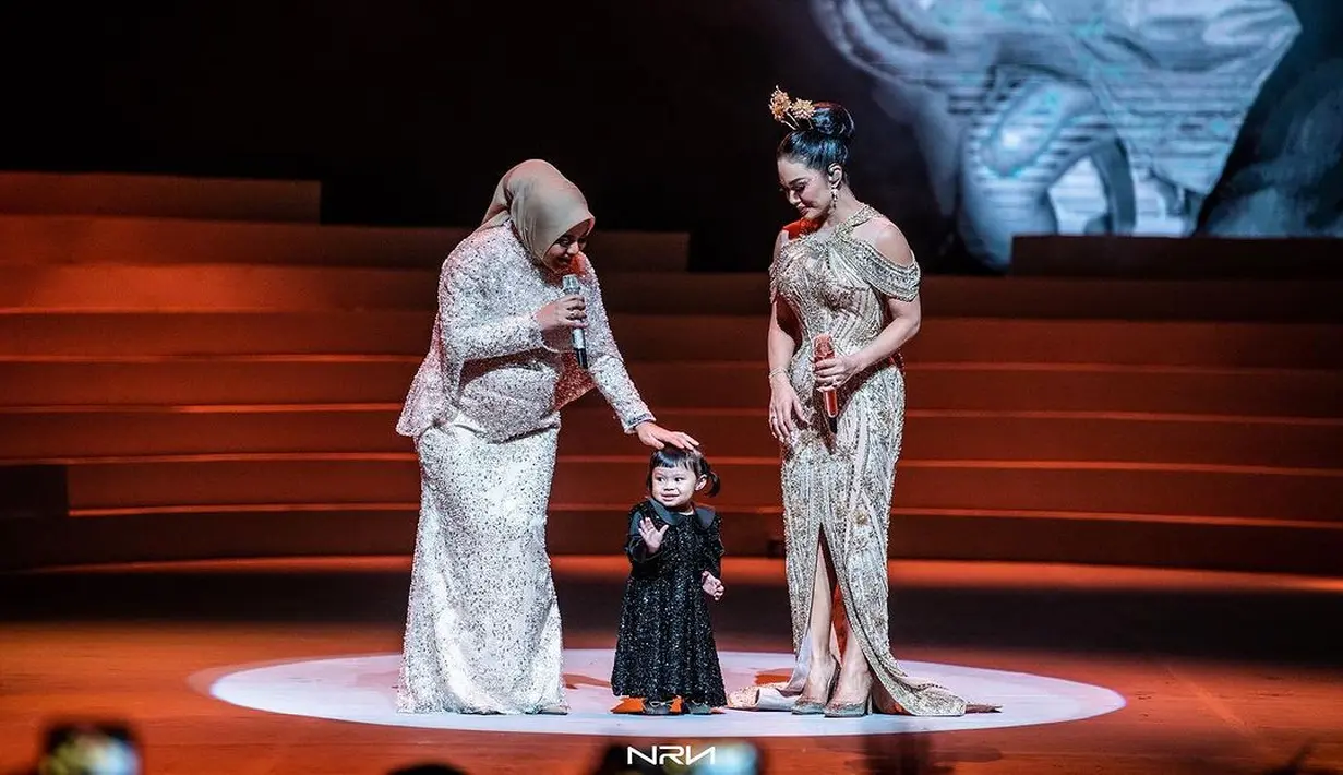 Ameena berdiri di depan Aurel mengenakan gaun panjang berhiaskan payet warna hitam. Sementara Amora mengenakan gaun satin dengan aksen puff di lengan, warna broken white.  [Instagram/aurelie.hermansyah]