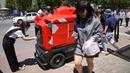 Pekerja mengambil pesanan mereka dari kendaraan pengiriman otonom yang dioperasikan oleh JD.com di jalanan Beijing, China, Jumat (28/5/2021). Raksasa e-commerce China JD.com meningkatkan operasi kendaraan pengiriman tak berawak. (AP Photo/Ng Han Guan)
