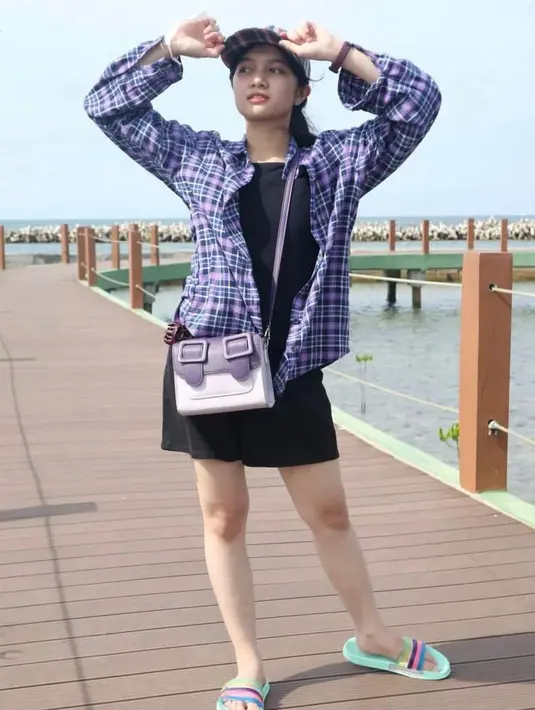 Kembali tampil feminin, kali ini ia memadukan mini dress hitam dengan plaid shirt ungu. @amaninaafiqah.