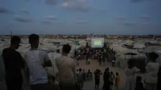 Warga Palestina menyaksikan siaran langsung pertandingan sepak bola Piala Dunia antara Spanyol dan Arab Saudi melalui layer lebar di Nuseirat, Jalur Gaza Tengah, Minggu 21 Juni 2026. (AP Photo/Abdel Kareem Hana)