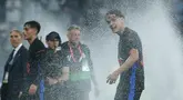 Pemain Barcelona, Hector Fort, menikmati siraman air dari lapangan usai mengunci gelar juara LaLiga 2024/2025 setelah mengalahkan Espanyol pada pertandingan ke-36 di RCDE Stadium, Jumat dini hari WIB (16/5/2025). (AP Photo/Joan Monfort)