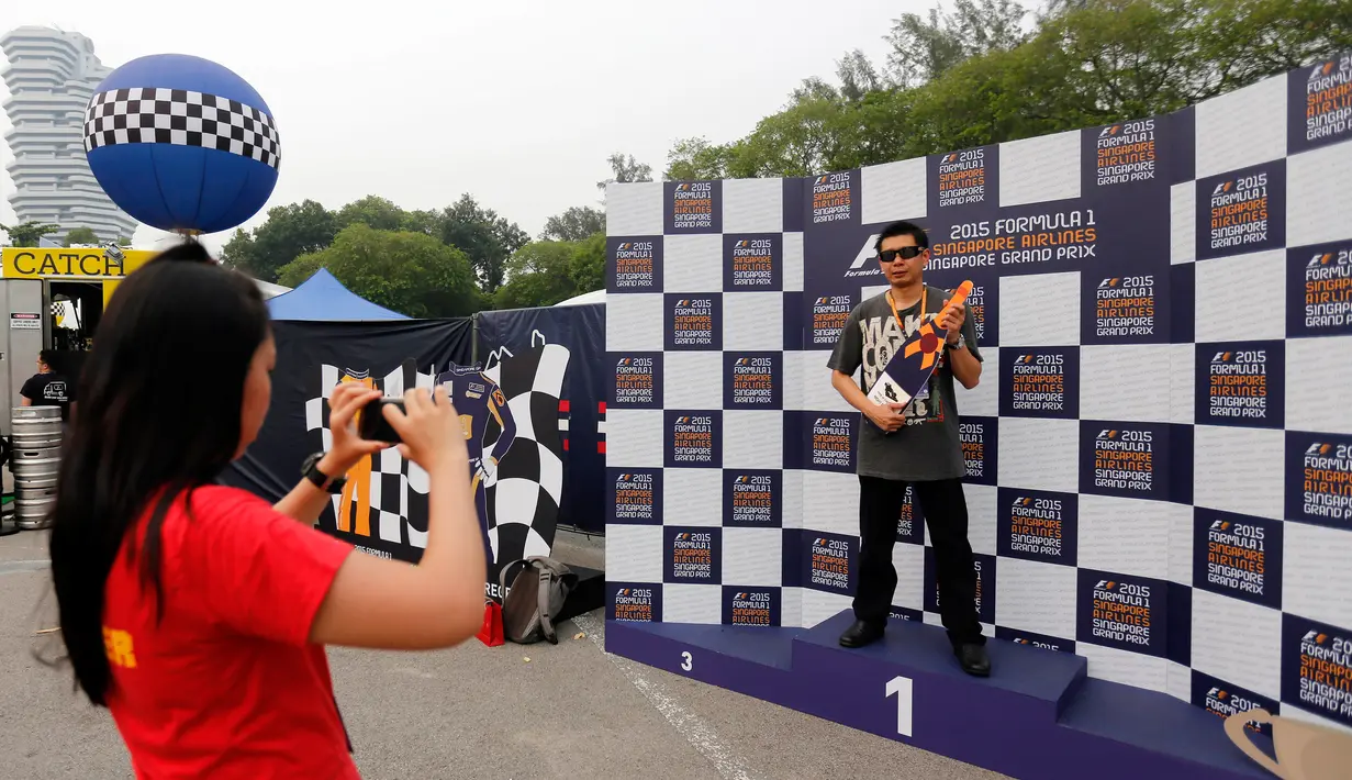Penonton berfoto jelang ajang sesi latihan Grand Prix Singapura F1 (18/9/2015). Kabut asap yang menyelimuti sirkuit tak menyurutkan pembalap untuk tetap melakukan pemanasan. (Singapore Grand Prix /Reuters)
