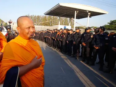  Dua Biksu berdiri di depan petugas saat melakukan penggeledahan Kuil Dhammakaya, Pathum Thani, Thailand (17/2). Kuil terbesar di Thailand ini digeledah untuk mencari biksu Phra Dhammachayo karena dakwaan pencucian uang. (AP Photo / Sakchai Lalit)