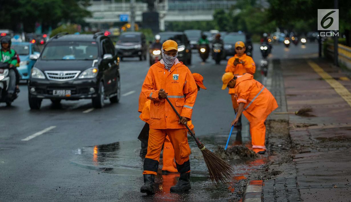 Petugas Dinas Kebersihan membersihkan genangan air usai hujan di kawasan jalan Sudirman, Jakarta, Rabu (22/11). Buruknya sistem drainase membuat petugas membersihkan genangan setiap kali hujan, meski dengan peralatan seadanya. (Liputan6.com/Faizal Fanani)