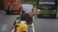 Sejumlah anak menggunakan kertas meminta bunyi klakson telolet ke bus yang lewat di jalan raya A Yani Surakarta, Solo, Kamis (22/12). Fenomena ini mendunia setelah beberapa artis dan tokoh terkenal dunia berkomentar di media sosial. (Liputan6.com/Gholib)
