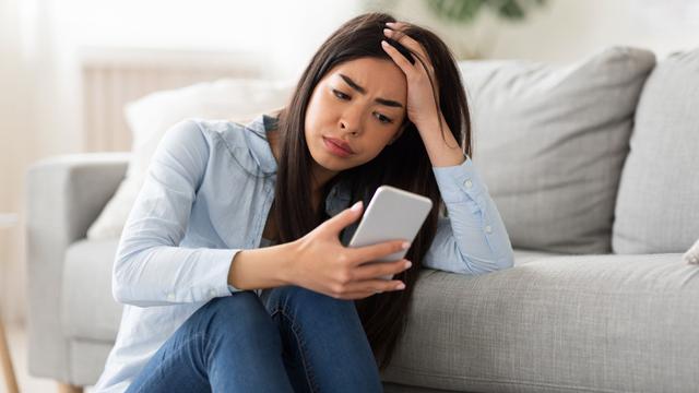 perempuan stres memegang ponsel