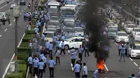 Sejumlah sopir taksi yang melakukan demo membakar ban dan memblokir jalan di tol dalam kota, Mampang, Jakarta, Selasa (22/3). Terlihat asap membumbung tinggi dari ban yang terbakar. (Liputan6.com/Johan Tallo)