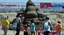 Pengunjung membawa serta keluarga mereka untuk menikmati keindahan seni patung pasir  di pameran Asahi Sand Sculpture, Yasashigaura, pantai Asahi, Tokyo, Sabtu (11/7/2015). Pameran ini digelar mulai Senin (6/7) lalu. (AFP PHOTO/Toshifumi Kitamura)