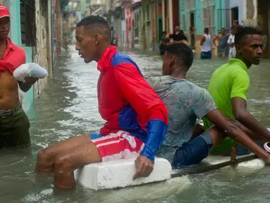 Sejumlah pria menggunakan styrofoam untuk melewati jalanan yang terendam banjir di Hanava, Kuba, Minggu (10/9). Badai irma yang melanda pantai timur Perairan Kuba pada Jumat waktu setempat menyebabkan sebagian kota terendam banjir. (AP/Ramon Espinosa)