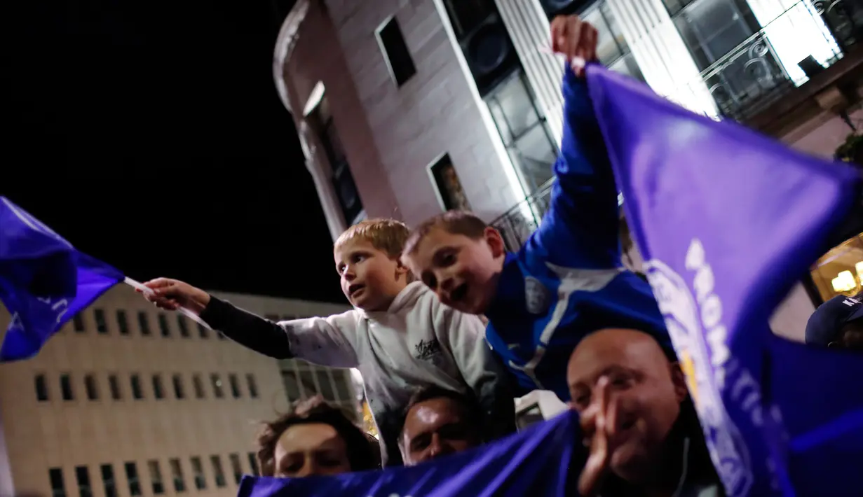 Sejumlah anak mengibarkan bendera Leicester City saat merayakan timnya meraih juara Liga Inggris setelah saingan terdekatnya Tottenham Hotspur bermain imbang 2-2 dengan Chelsea di sebuah pub di Leicester,(3/5).  (Reuters/Eddie Keogh)