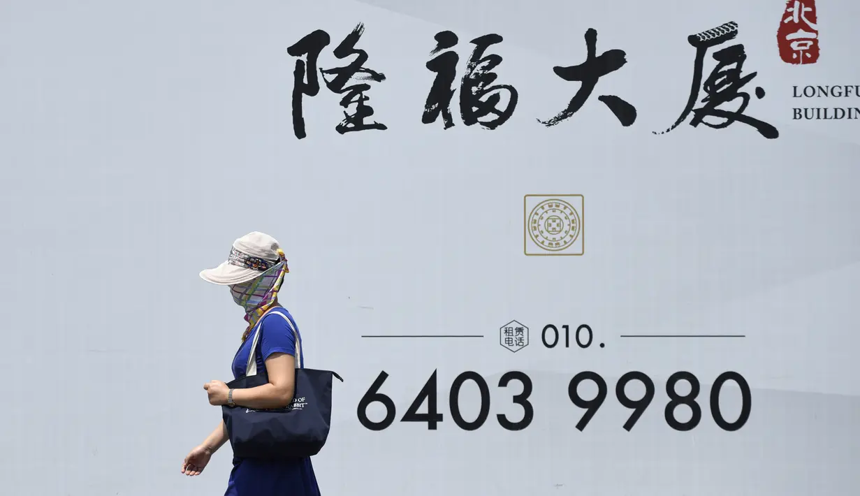 Seorang wanita mengenakan topi dan penutup wajah untuk menghadapi teriknya panas matahari di sebuah jalanan di Beijing, Rabu (12/7).Sebanyak 21 provinsi di China diterpa gelombang panas dengan suhu maksimum mencapai 50 derajat Celsius. (WANG ZHAO/AFP)