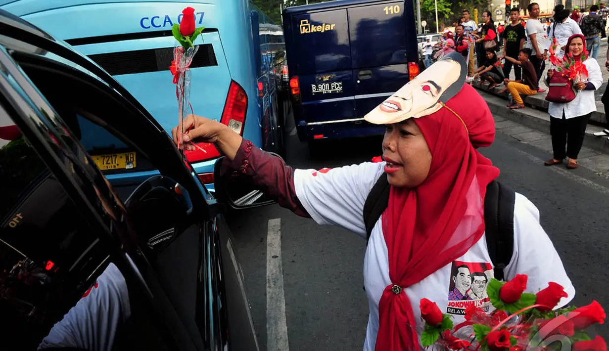 Relawan Jokwi-JK saat membagikan bunga kepada pengendara yang melintas di Bundaran HI, Jakarta, (17/10/14). (Liputan6.com/Johan Tallo)