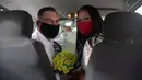 Ayrton (kiri) dan Natasha dengan mengenakan masker berpose setelah pernikahan drive-thru mereka di kantor pencatatan sipil di Santa Cruz, Rio de Janeiro, Brasil, 28 Mei 2020. Fasilitas ini untuk memudahkan pasangan yang ingin mengesahkan hubungan saat pandemi covid-19. (AP/Silvia Izquierdo)