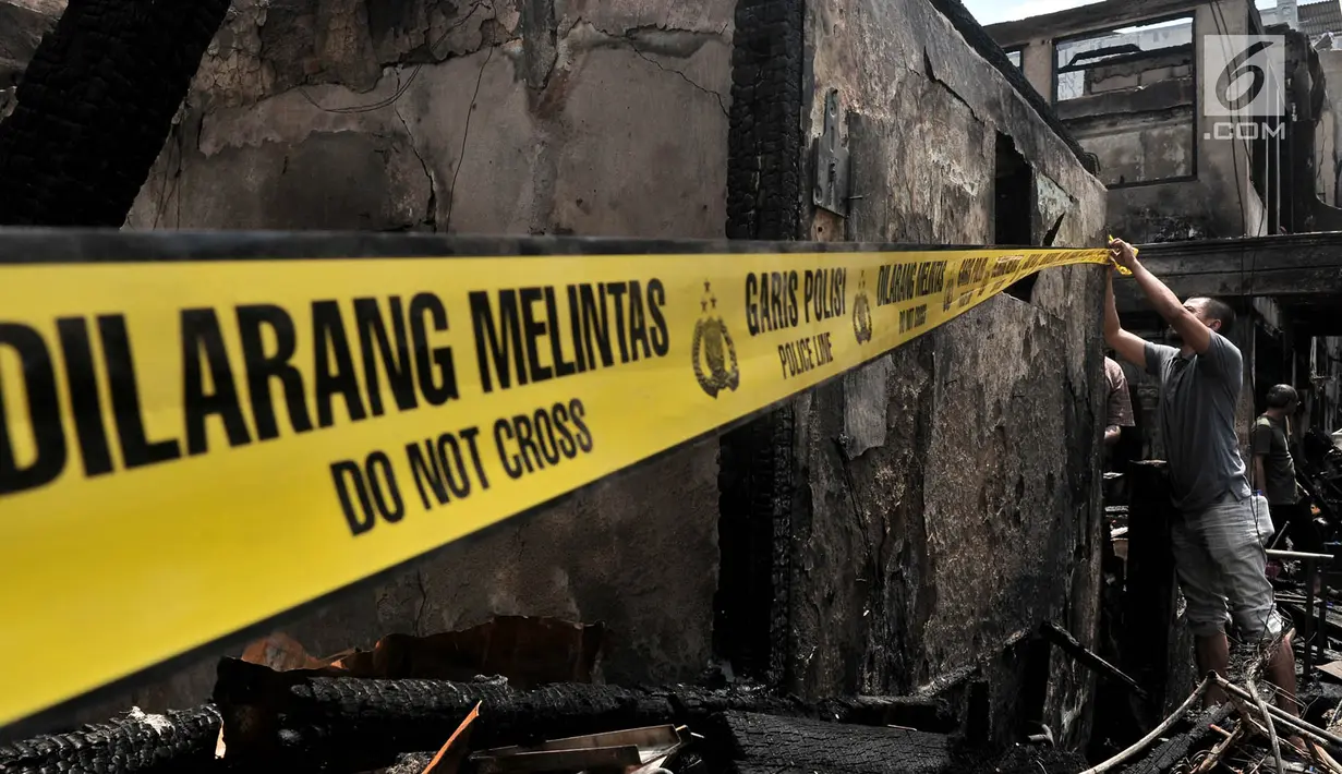 Warga memasang garis polisi di depan rumah yang merupakan titik awal kebakaran di kawasan Krukut, Tamansari, Jakarta, Selasa (26/2). Sedikitnya 30 rumah di 4 RT hangus setelah api membakar kawasan padat penduduk tersebut. (Merdeka.com/Iqbal S Nugroho)