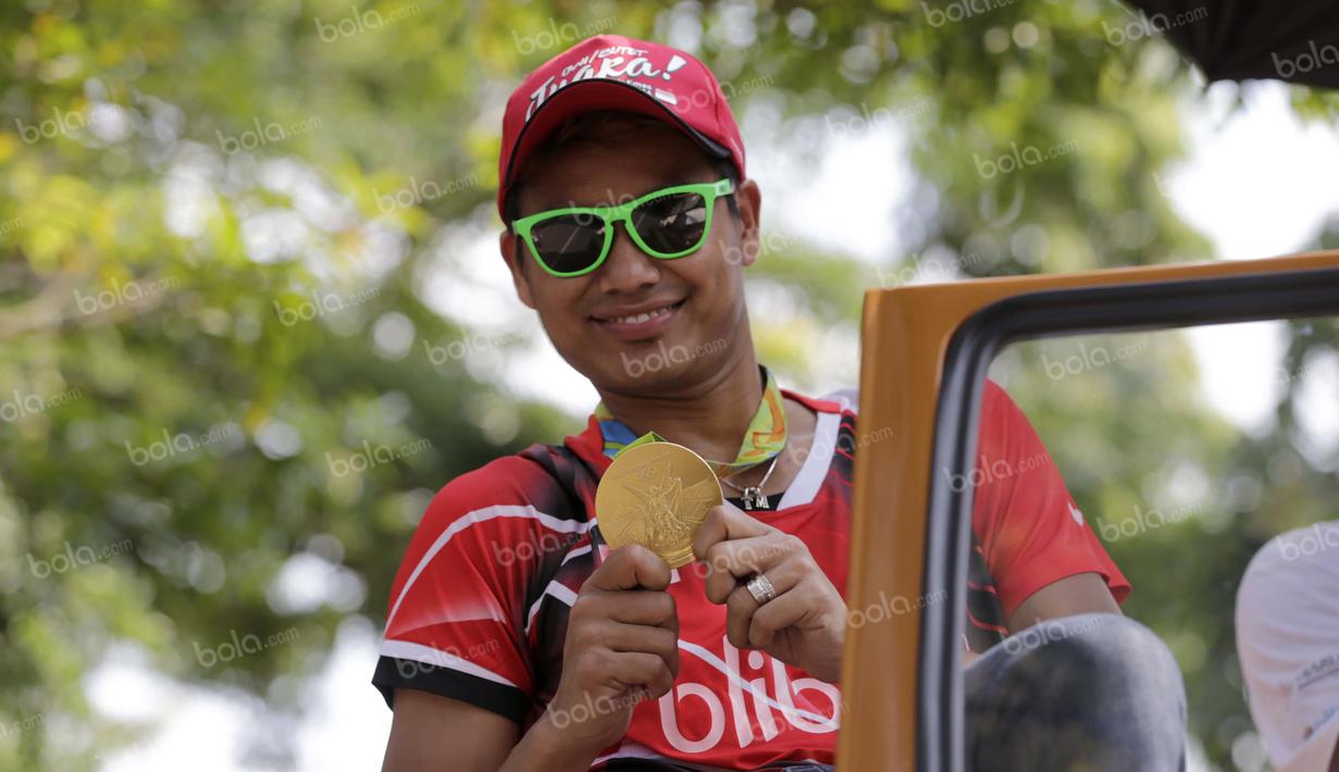 Tontowi Ahmad memamerkan medali emas Olimpiade Rio 2016 di tengah kemeriahan penyambutan kirab bersama Liliyana Natsir di kota Kudus, Kamis (1/9/2016). (Bola.com/Arief Bagus).