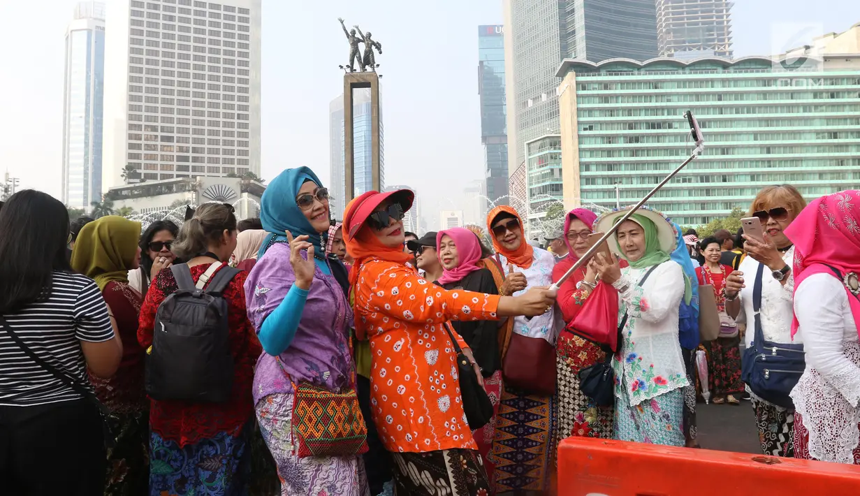 Emak-emak dari masyarakat pencinta kebaya dan sarung Indonesia berselfie saat mengikuti parade di Bundaran HI, Jakarta, Minggu (28/7/2019). Parade tersebut bertujuan untuk mengajak masyarakat agar mencintai busana tradisional khas Indonesia. (Liputan6.com/Angga Yuniar)