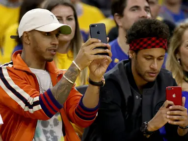 Pembalap Formula 1, Lewis Hamilton dan pemain Barcelona, Neymar Jr merekam pertandingan gim kedua Final NBA antara Cleveland Cavaliers melawan Golden State Warriors di Oracle Arena, Oakland, California, AS, (4/6). (Ezra Shaw/Getty Images/AFP)